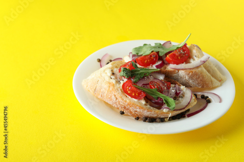 Plate with bruschetta snacks on yellow background