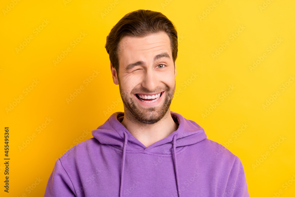 Photo of flirty charismatic guy blink eye suggest choice wear purple hoodie isolated yellow color background Photo of flirty charismatic guy blink eye suggest choice wear purple hoodie isolated yellow color background