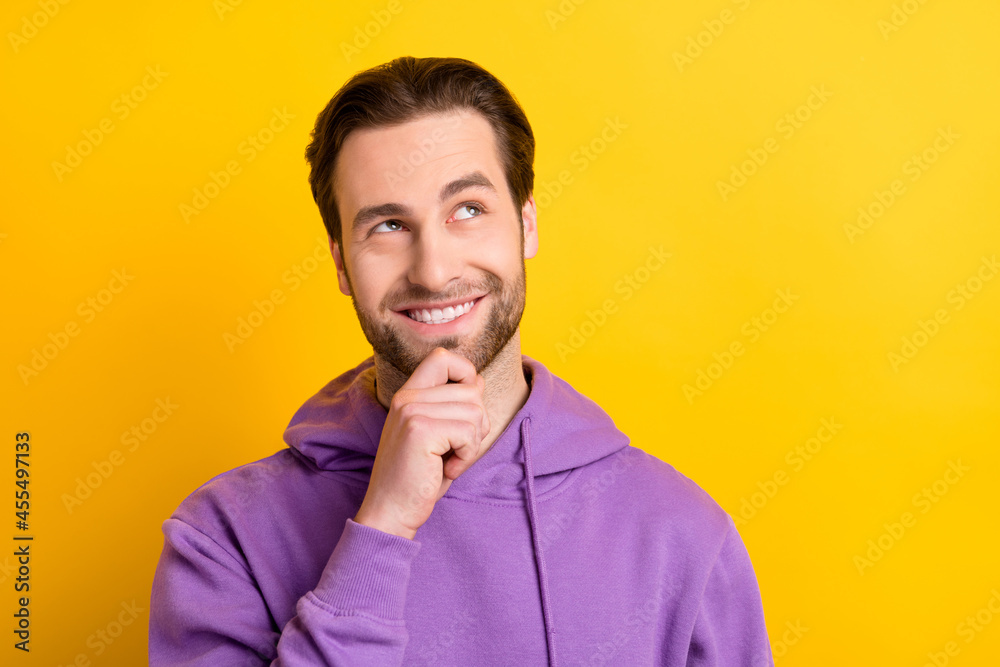 Obraz premium Photo of minded thoughtful guy look up empty space finger chin wear purple hoodie isolated yellow color background