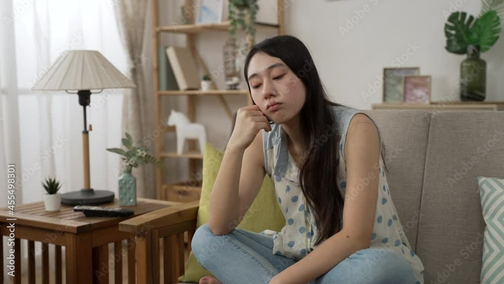 unhappy Chinese female sitting alone on living room sofa is holding face and staring into distance feeling bored about staying at home during covid19 quarantine unhappy Chinese female sitting alone on living room sofa is holding face and staring into distance feeling bored about staying at home during covid19 quarantine