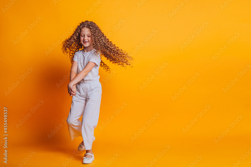 Obraz premium beautiful girl spinning in white t-shirt on yellow background in studio 