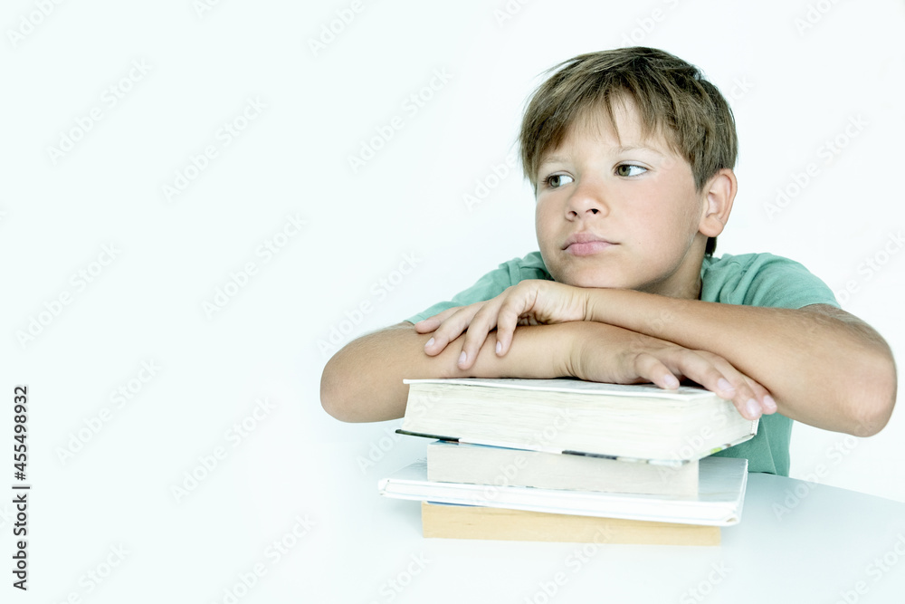 Sad boy with book does school homework. Back to school. Unhappy schoolboy with textbooks. Distance learnin Sad boy with book does school homework. Back to school. Unhappy schoolboy with textbooks. Distance learnin
