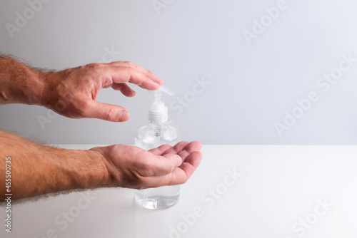Man hands using hidroalcoholic gel dispenser to disinfect against viruses and stay healthy photo