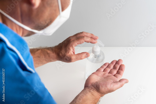 Man hands with mask using hidroalcoholic gel dispenser to disinfect against viruses and stay healthy photo