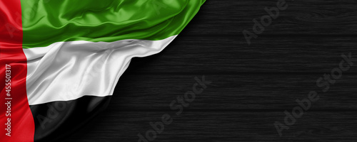 Close Up of United Arab Emirates flag on the black wooden background 3D render