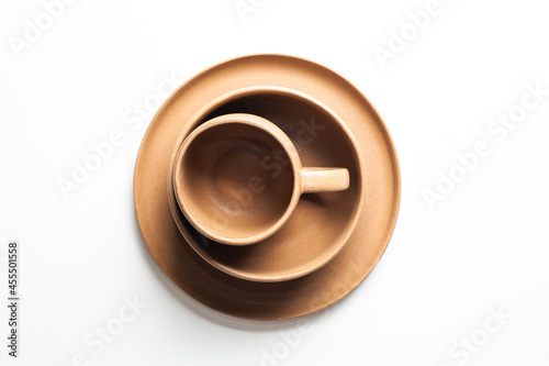 Overlapping of brown pottery coffee cup, bowl and plate, isolated on white