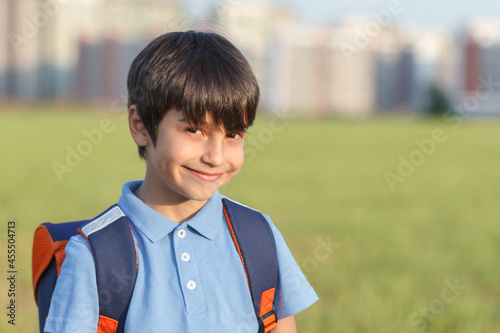 Returning to school concept, portrait of happy boy with backpack, school child waiting for school bus, primary school student, on the way to school