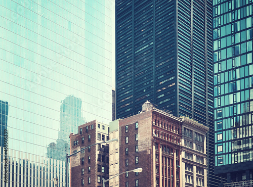 Old townhouse buildings between modern skyscrapers in New York  retro color toned picture  USA.