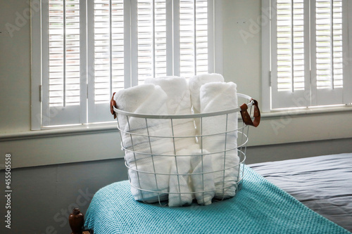 Valokuva A basket of organized clean rolled white towels for guests sitting on a bed in a