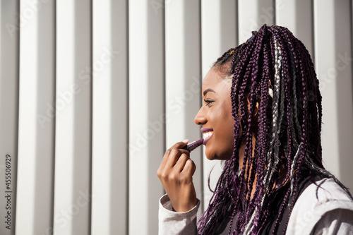 Black woman with braids applying lipstick photo