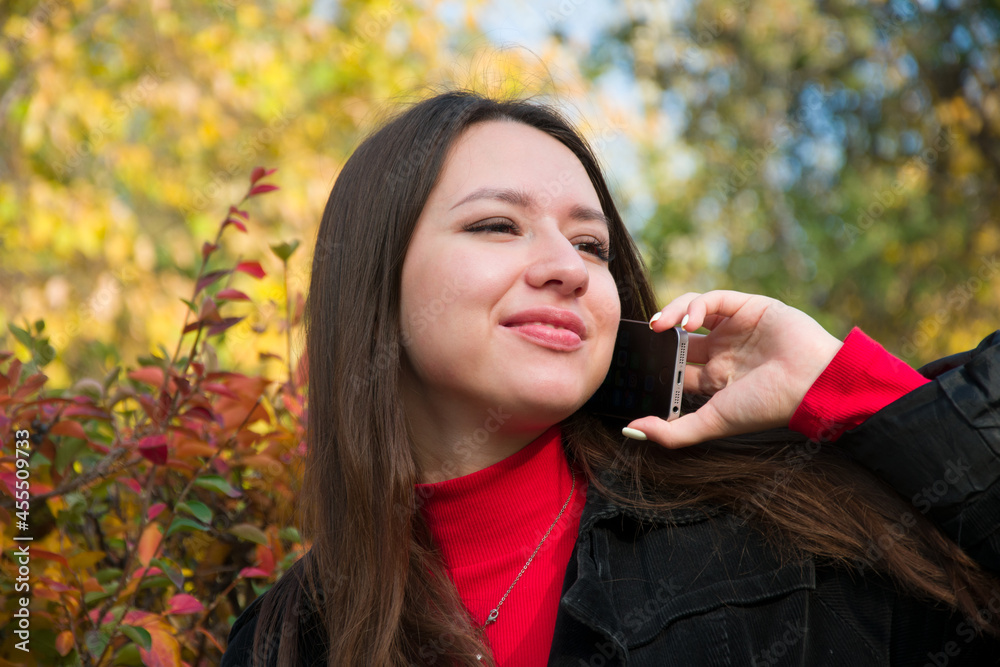 Fototapeta premium Pensive woman talking on phone in autumn park