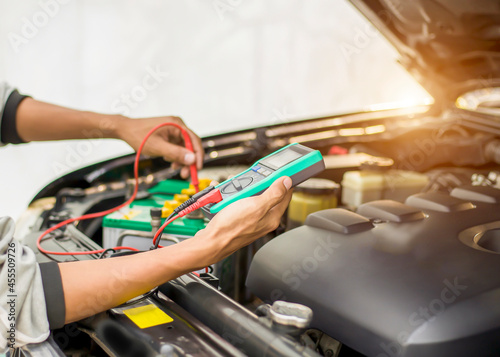 A technician is checking the car battery for availability.; 