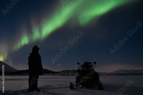 Fotografie snowmobile and man with aurora borealis
