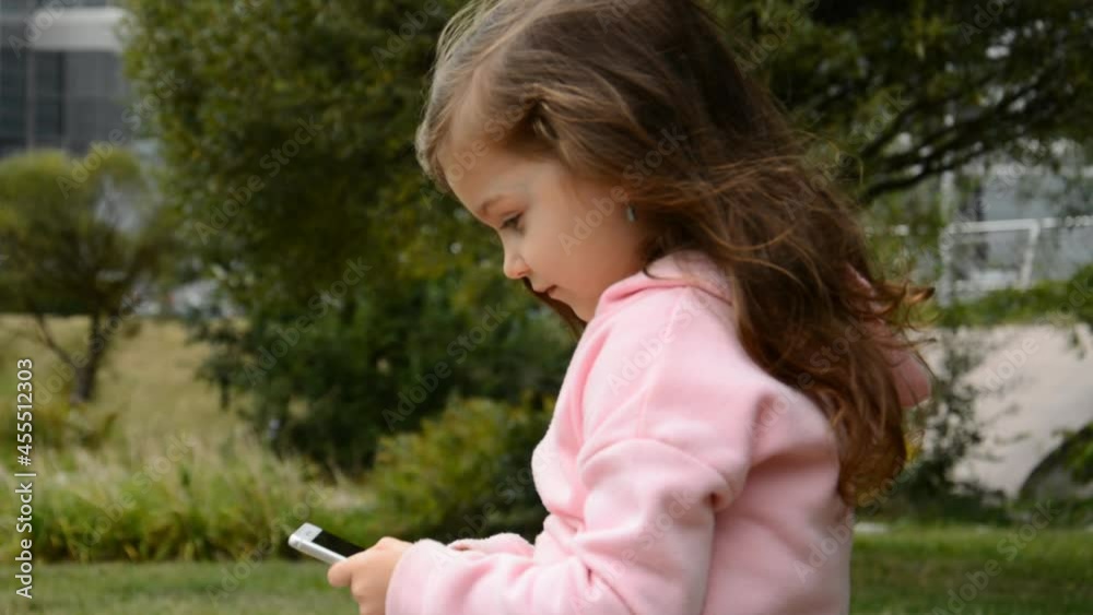 Little caucasian Girl Using Mobile Phone outside Little caucasian Girl Using Mobile Phone outside