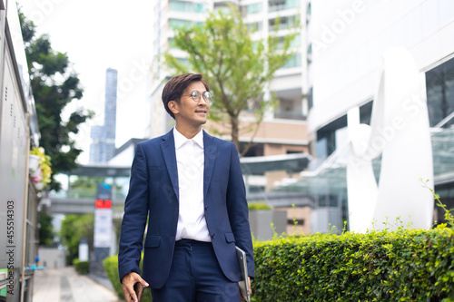 Asian businessman wearing suit jacket walking go to work in morning outdoor.