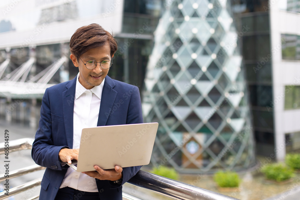 Handsome asian businessman working outdoors with computer