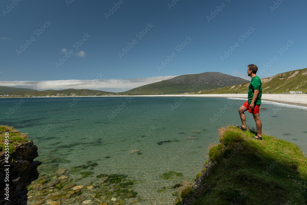 Young traveler standing on cliff admiring Keel Beach in Achill Island Ireland