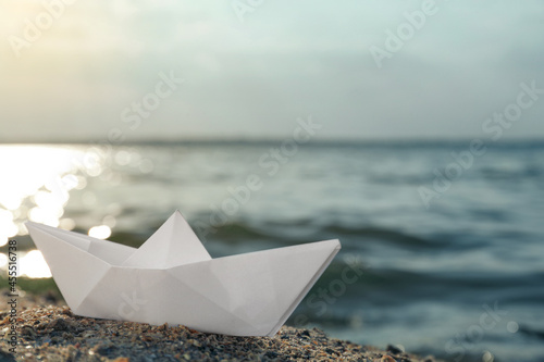 White paper boat near river on sunny day, space for text