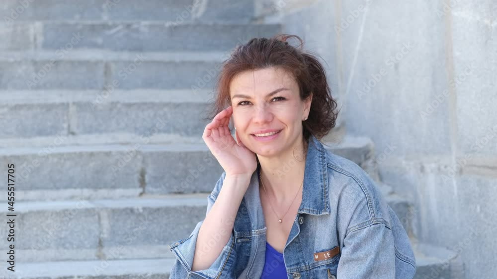 woman looking to camera and smiling outdoors on sunny summer day. Happy female at street. Close up woman looking to camera and smiling outdoors on sunny summer day. Happy female at street. Close up