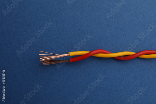 Two twisted electrical wires on blue background, closeup