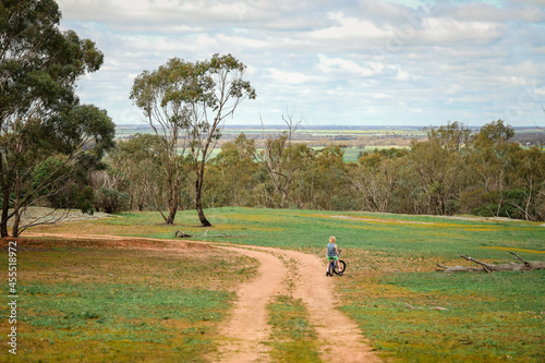 Boy riding bike on dirt track with view of fields in the distance