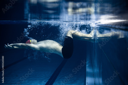 One male swimmer practicing and training at pool, indoors. Underwater view of swimming movements details. Healthy lifestyle, power, energy, sports movement concept.