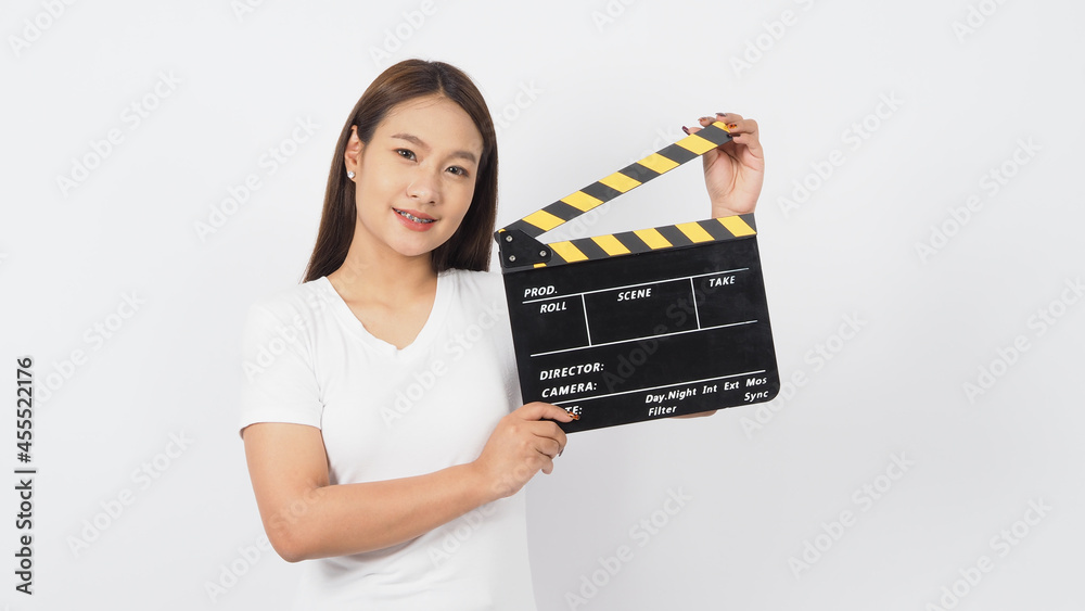 Asian woman is holding black clapper board or movie clapperboard and wear white t shirt on white background. Asian woman is holding black clapper board or movie clapperboard and wear white t shirt on white background.