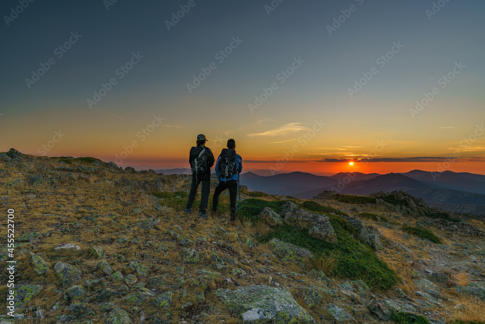 Senderistas observando el ocaso desde la montaña Senderistas observando el ocaso desde la montaña