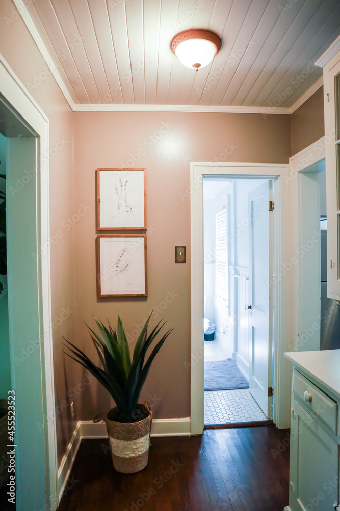 a tan colored hallway with a shiplap paneled ceiling and artwork on the walls. a tan colored hallway with a shiplap paneled ceiling and artwork on the walls.