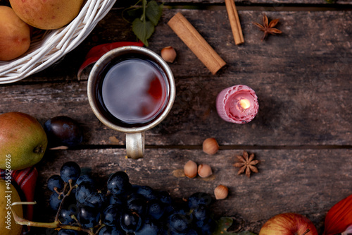 Rustic cozy still life: cup of tea, fruits, vegetables, hazelnuts and cinnamon sticks top view. Autumn aesthetic still life with cup and candle. Thanksgiving Day concept.
