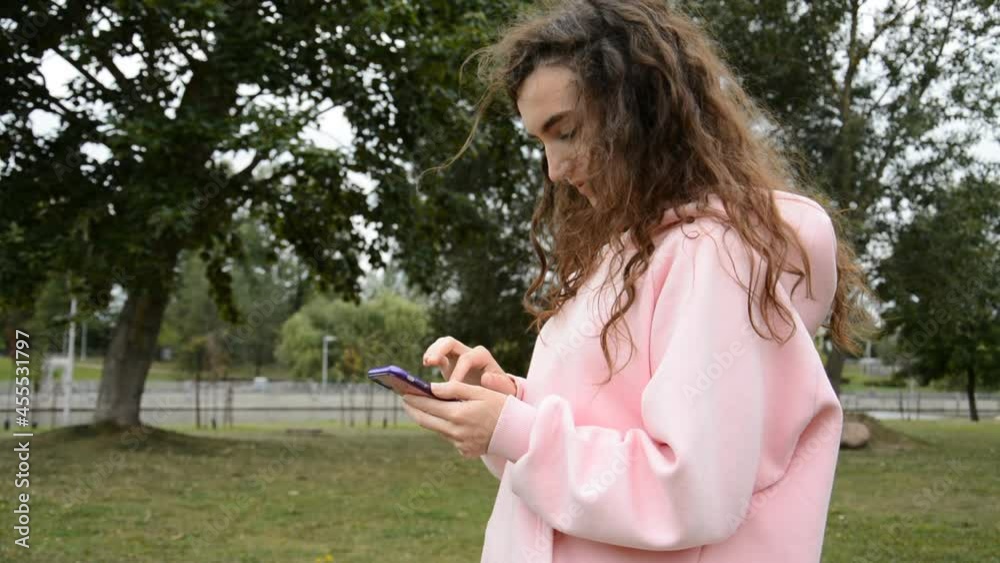 Beautiful girl writes a message on her smartphone in the autumn park Beautiful girl writes a message on her smartphone in the autumn park