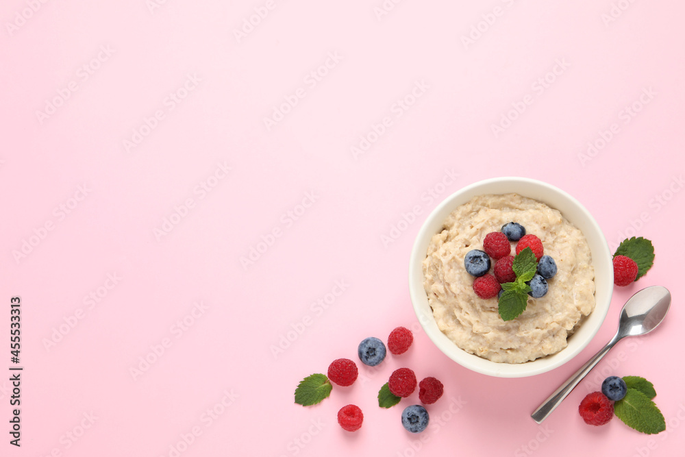 Tasty oatmeal porridge with raspberries and blueberries in bowl on pink background, flat lay. Space for text Tasty oatmeal porridge with raspberries and blueberries in bowl on pink background, flat lay. Space for text
