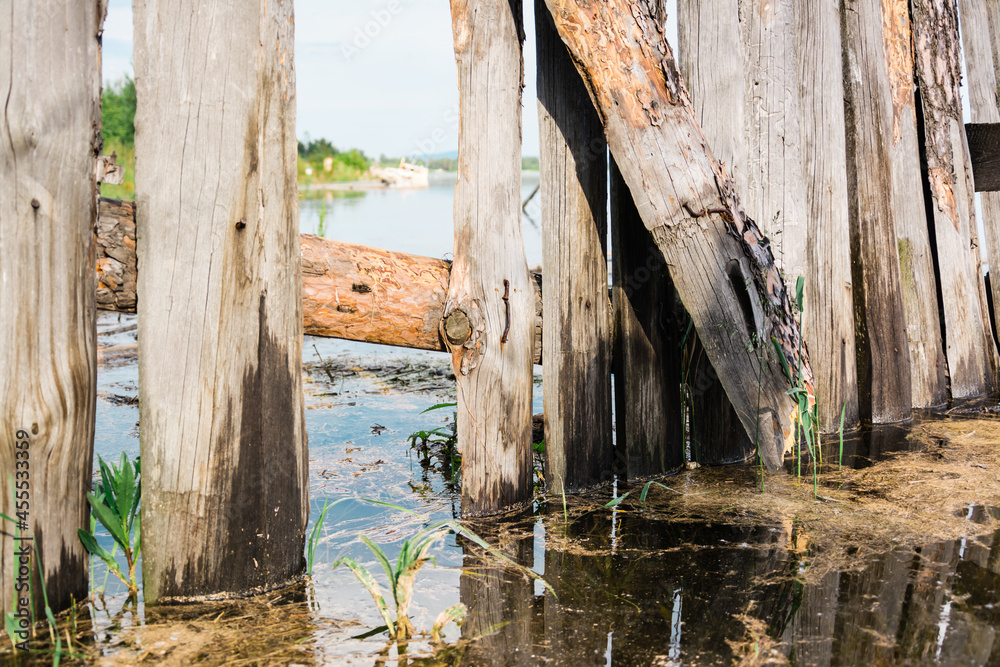 An old broken wooden fence is flooded by a flood on the river bank. Disaster An old broken wooden fence is flooded by a flood on the river bank. Disaster