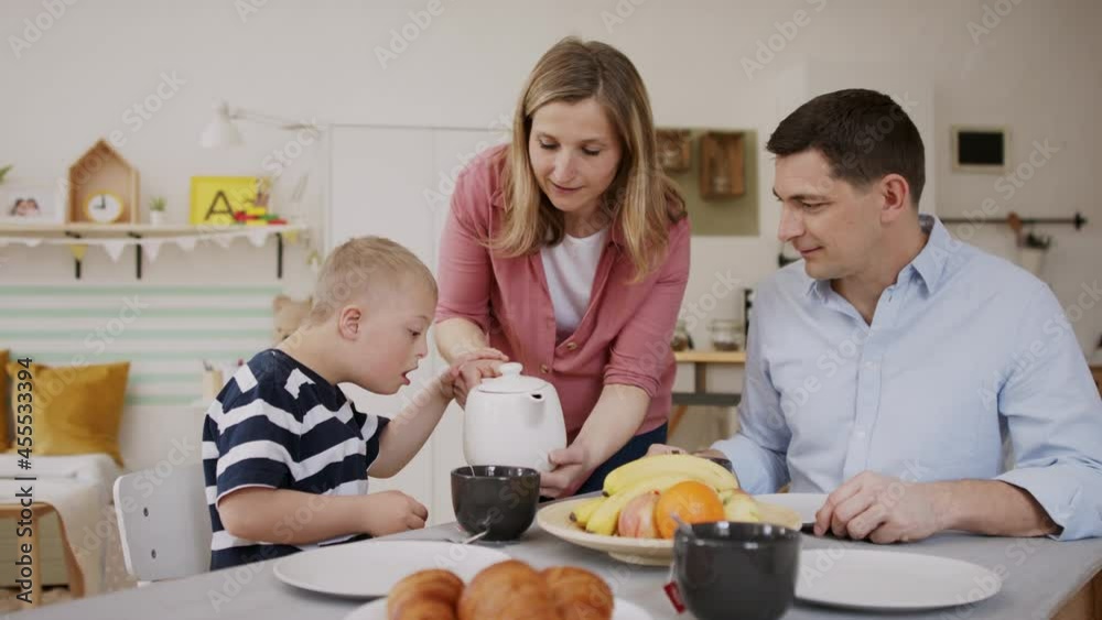 Happy family with down syndrome son at the table, having breakfast. Happy family with down syndrome son at the table, having breakfast.