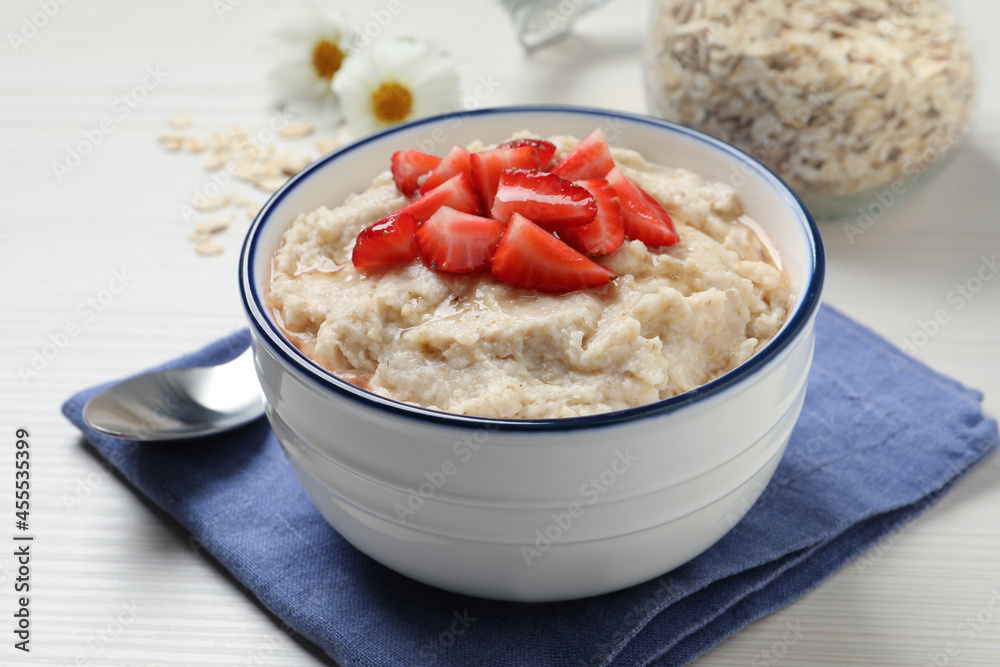 Tasty oatmeal porridge with strawberries served on white wooden table Tasty oatmeal porridge with strawberries served on white wooden table