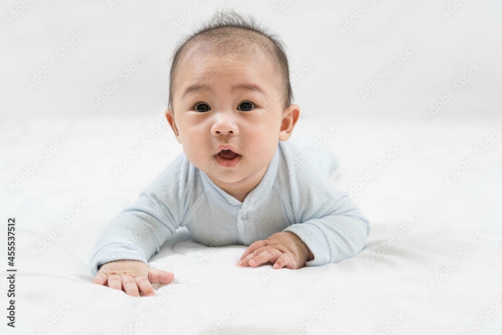 Morning Time.Adorable newborn kid during tummy time smiling happily at home.Portrait of cute smiling happy asian baby boy crawling on bed on the white blanket in bedroom. Morning Time.Adorable newborn kid during tummy time smiling happily at home.Portrait of cute smiling happy asian baby boy crawling on bed on the white blanket in bedroom.