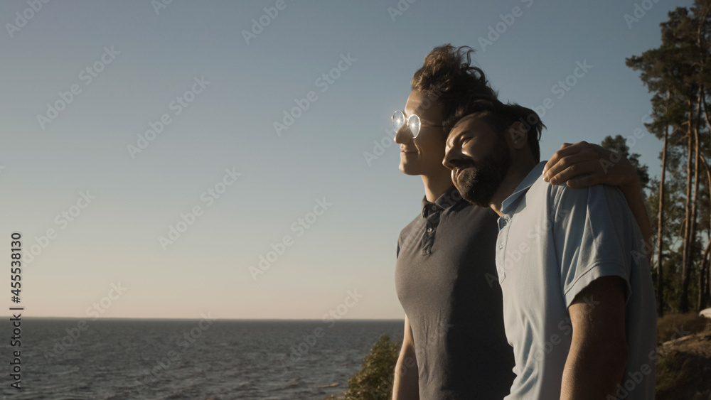 Two boyfriends in love hugging and enjoying tranquil seascape together, lgbt
