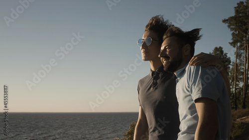 Happy gay couple hugging and admiring sea view, making future plans together