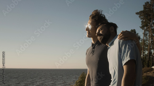 Two boyfriends in love hugging and enjoying tranquil seascape together, lgbt