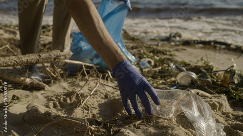 Environmental volunteer collecting plastic waste on beach, nature preservation