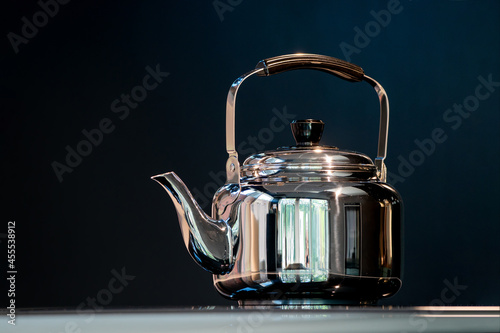 Stainless Water Crow or Vintage Kettle tea pot on electronic stove in modern dark blue background. photo