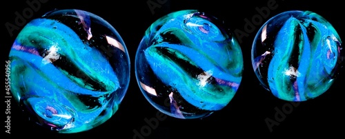 Bolas de gude azuis de tamanhos diferente e fundo preto.  photo