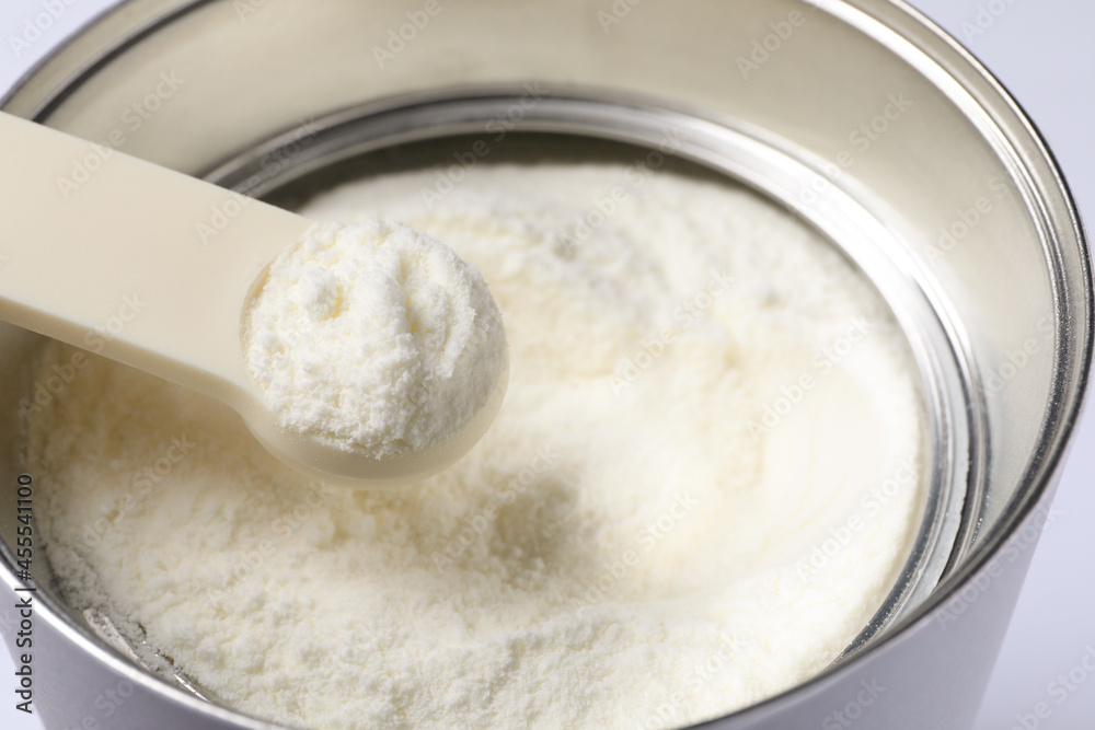 Scoop of powdered infant formula over can, closeup. Baby milk Scoop of powdered infant formula over can, closeup. Baby milk
