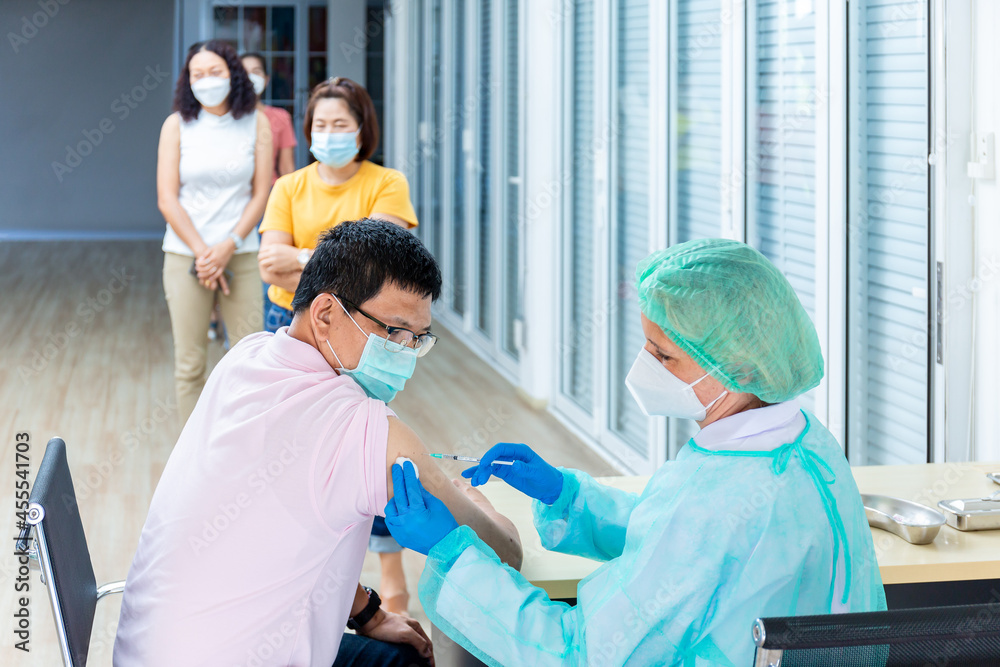 Obraz premium medicine, vaccination and healthcare concept - doctor wearing face protective medical mask for protection from virus disease with syringe doing injection of vaccine to a patient