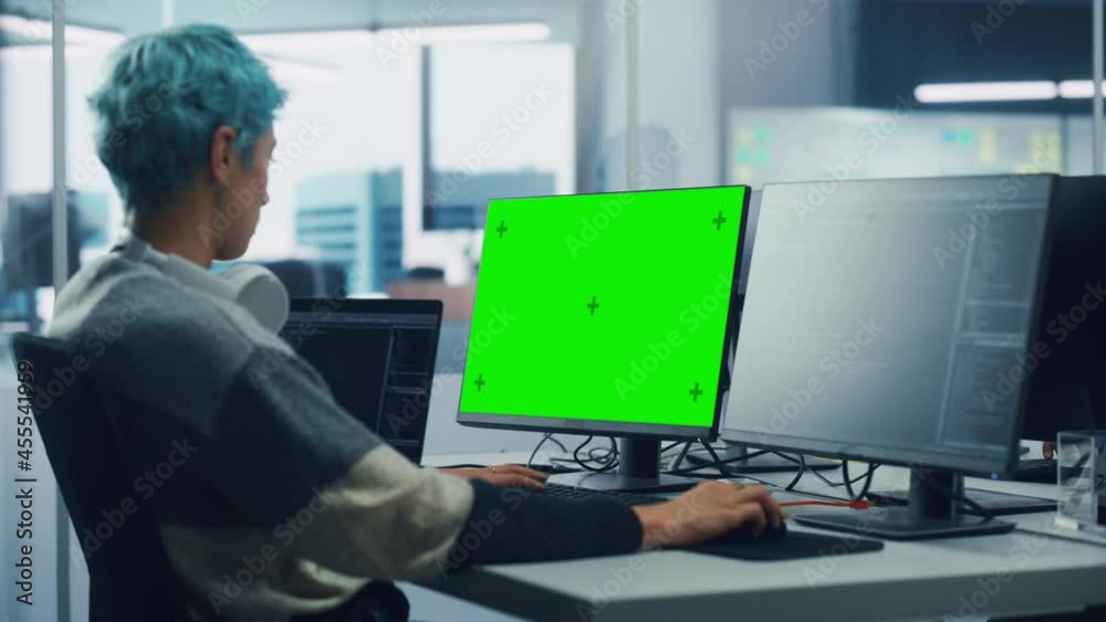 In Diverse Office: Female Programmer is Working on Green Screen Computer, Chroma key and Coding Language User Interface. Digital Entrepreneur Creating Software, e-Commerce App Design. Over Shoulder In Diverse Office: Female Programmer is Working on Green Screen Computer, Chroma key and Coding Language User Interface. Digital Entrepreneur Creating Software, e-Commerce App Design. Over Shoulder