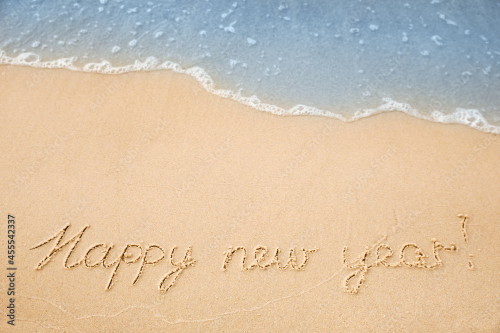 Fototapeta premium Sandy beach with text Happy New Year washed by sea, above view