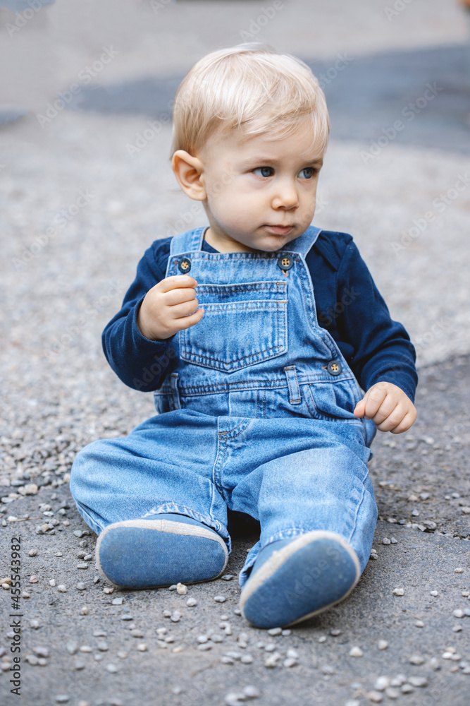 Little blond haired baby sitting on the ground Little blond haired baby sitting on the ground