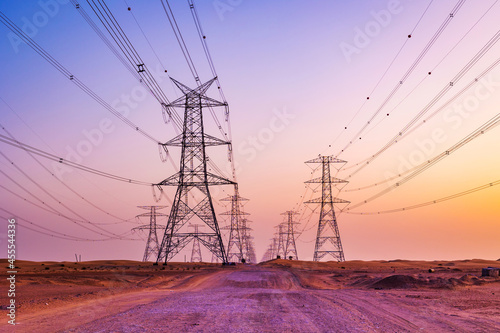 High voltage tower with electricity transmission power lines against the colorful sky, low angle view. Dubai Al Qudra Desert United Arab Emirates. photo