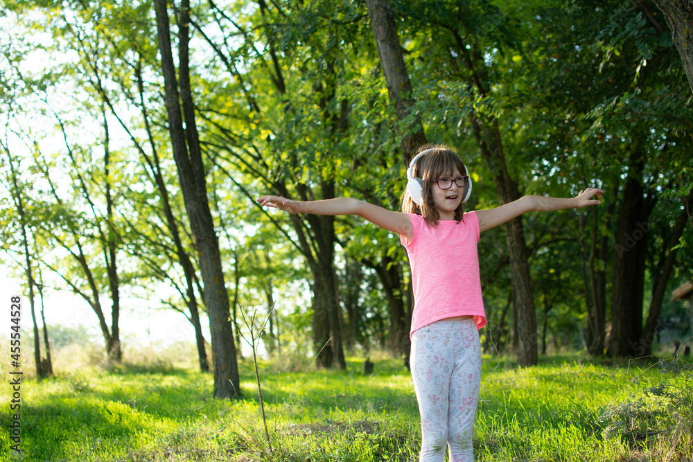 Adorable girl with Headphones and Hands Up on the Nature Background. Headphones with Hands Up on the Nature Background.