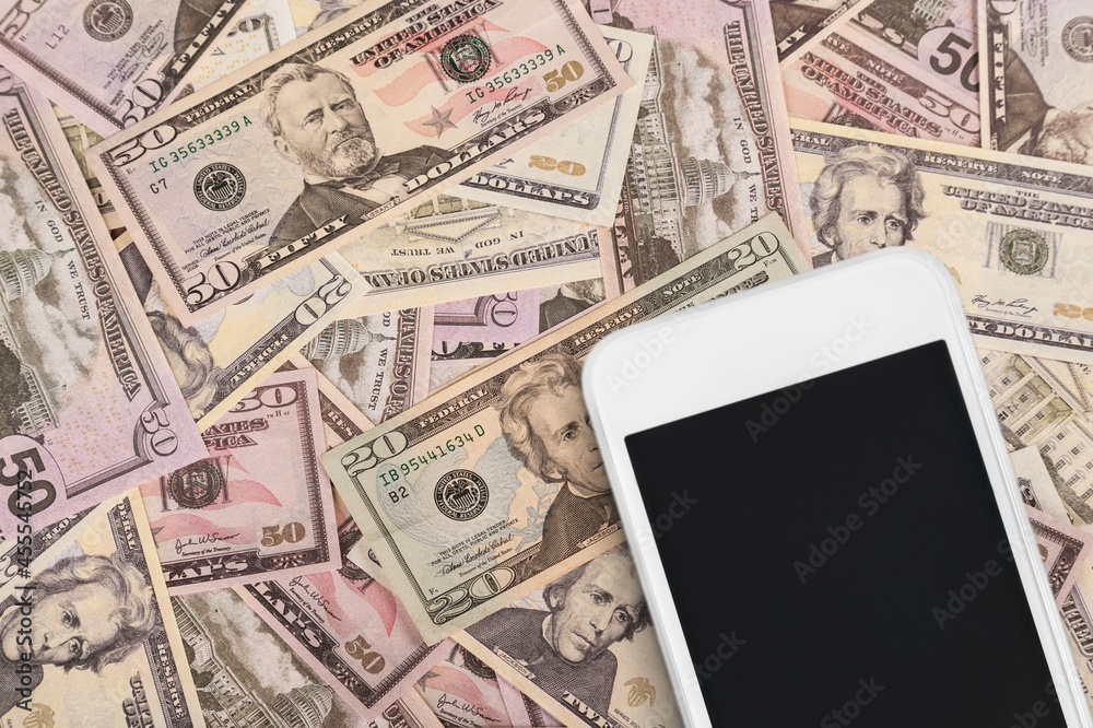 Modern smartphone with a blank screen and money banknotes. Investing and trading Modern smartphone with a blank screen and money banknotes. Investing and trading